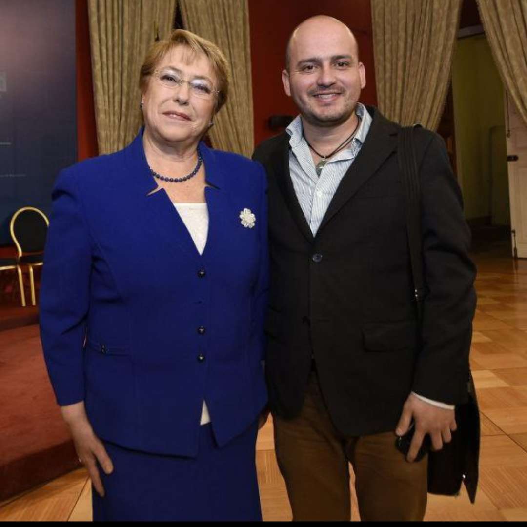 Fotografía de Yesid Castaño junto a la expresidenta Michelle Bachelet, simbolizando su influencia en la política migratoria chilena